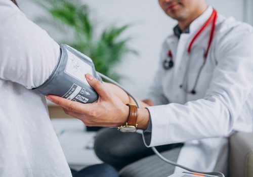 Young male psysician with patient measuring blood pressure